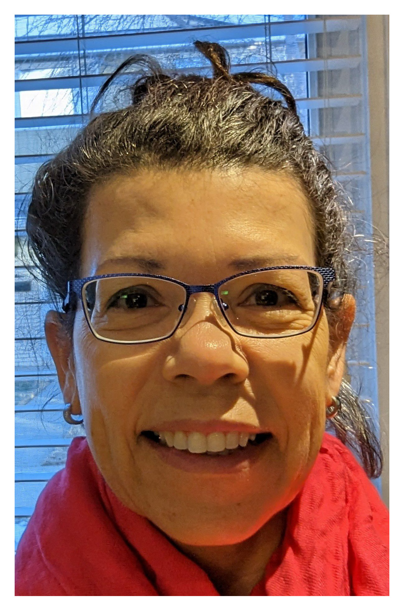 Close-up of a smiling woman wearing glasses and a red scarf.
