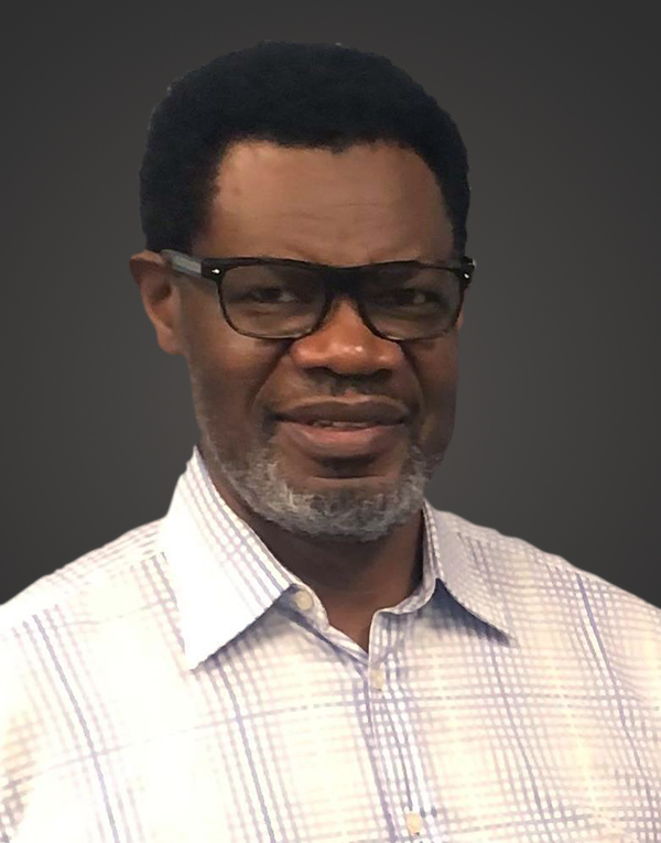 Portrait of a smiling man wearing glasses and a checkered shirt.